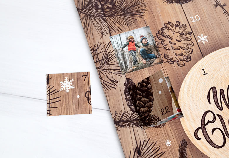 Personalised photo advent calendar with a wooden theme, featuring pinecone and snowflake designs. Two open windows reveal custom photos.