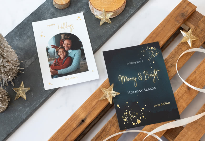 Fotogrusskarten mit Goldfolienprägung: eine weiße Karte mit einem Foto und "Happy Holidays" in Gold und eine schwarze Karte mit dem goldenen Text "Merry & Bright".