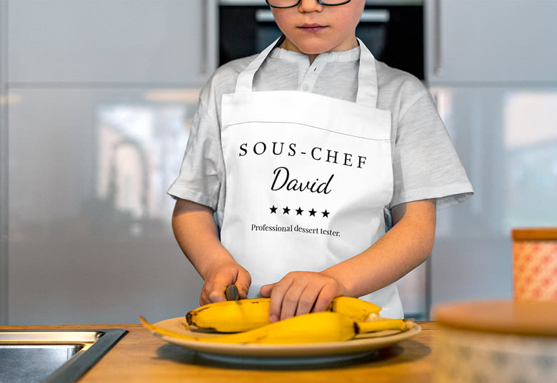 Hvit barneforkle med "SOUS-CHEF David" personalisering og "Professional dessert tester" tekst.