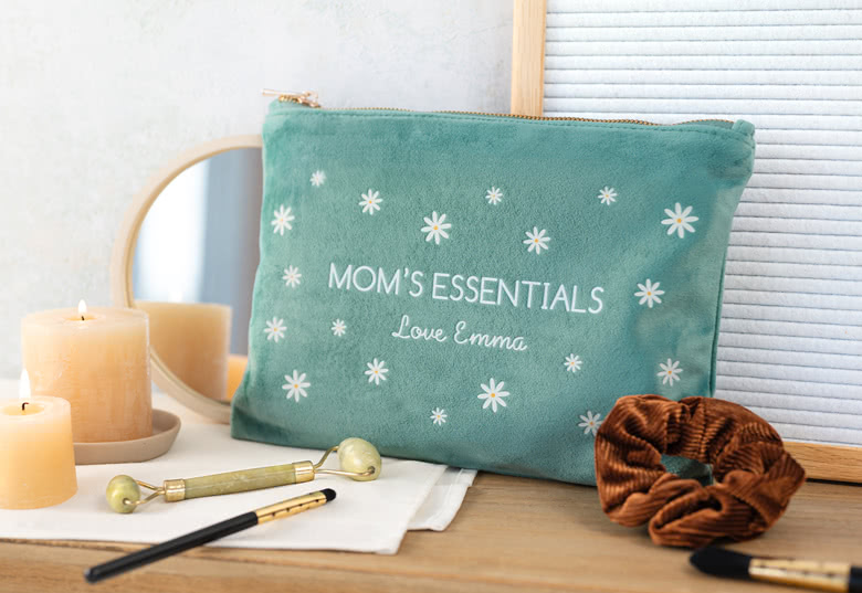 Grön velournecessär med vita prästkragemönster, personifierad med "MOM'S ESSENTIALS" och "Love Emma" i vit text.