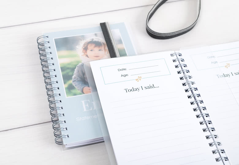 Cahiers à spirale personnalisés avec une couverture bleu clair présentant une photo d'enfant et un espace pour la date et l'âge. Les pages intérieures ont des sections lignées avec l'en-tête "Today I said...".