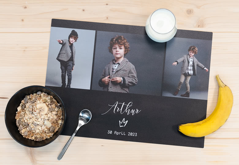 Customised black placemat with three photo panels and white text 'Arthur, 30 April 2023'.