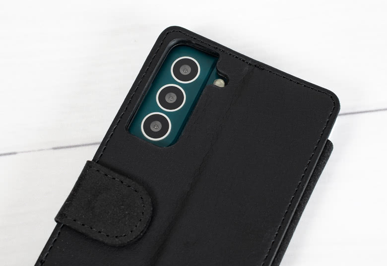 Coque portefeuille Samsung noire avec découpes pour caméra visibles, rabat fermé, sur une surface en bois.